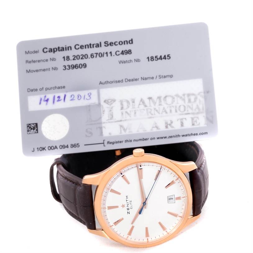 The image shows the face and strap of a Zenith Captain 18.2020.670 Men's Rose Gold White Dial 18.2020.670 Men's Rose Gold White Dial Central Second watch, along with its warranty card angled behind it.