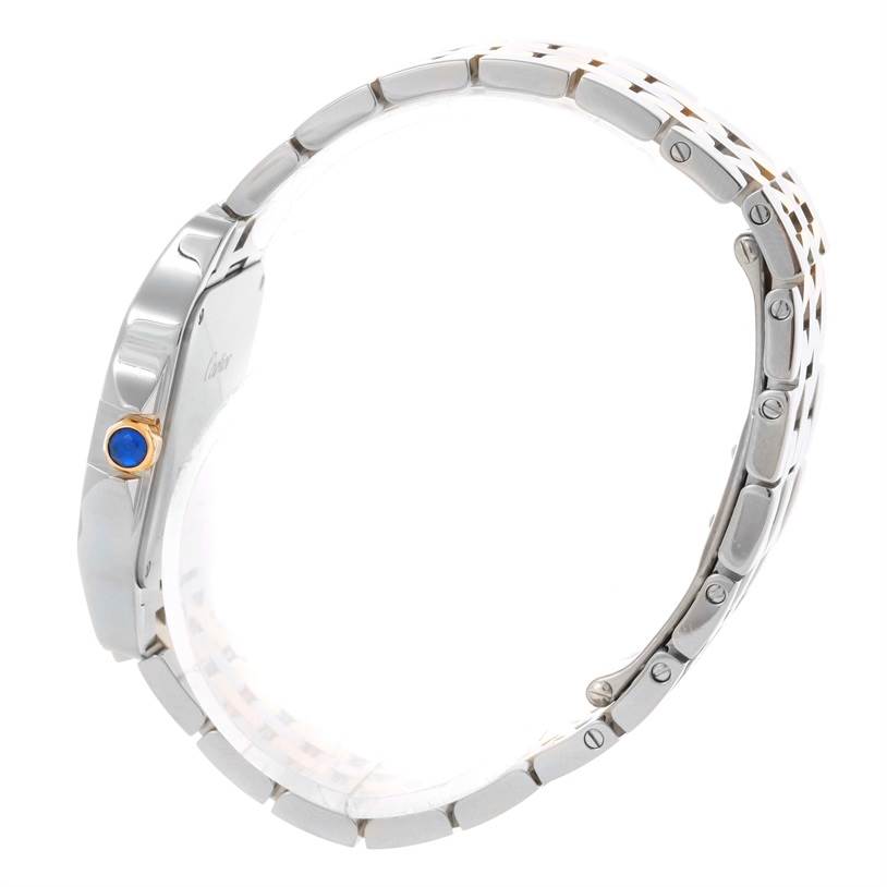 The image shows the side profile of a Cartier Santos Demoiselle W25067Z6 Women's Steel and Gold (two tone) Silver Dial W25067Z6 Women's Steel and Gold (two tone) Silver Dial watch, highlighting the bracelet and crown with a blue cabochon.