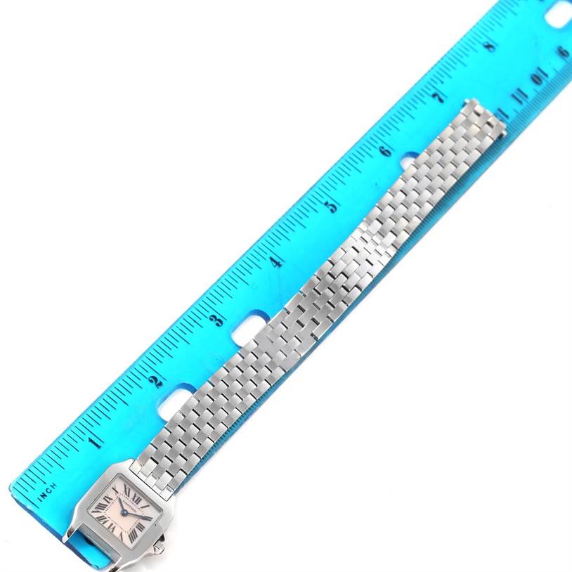 The Cartier Santos Demoiselle W25075Z5 Women's Stainless Steel Mother of Pearl Dial W25075Z5 Women's Stainless Steel Mother of Pearl Dial watch is shown at a top-down angle with its band aligned next to a blue ruler.