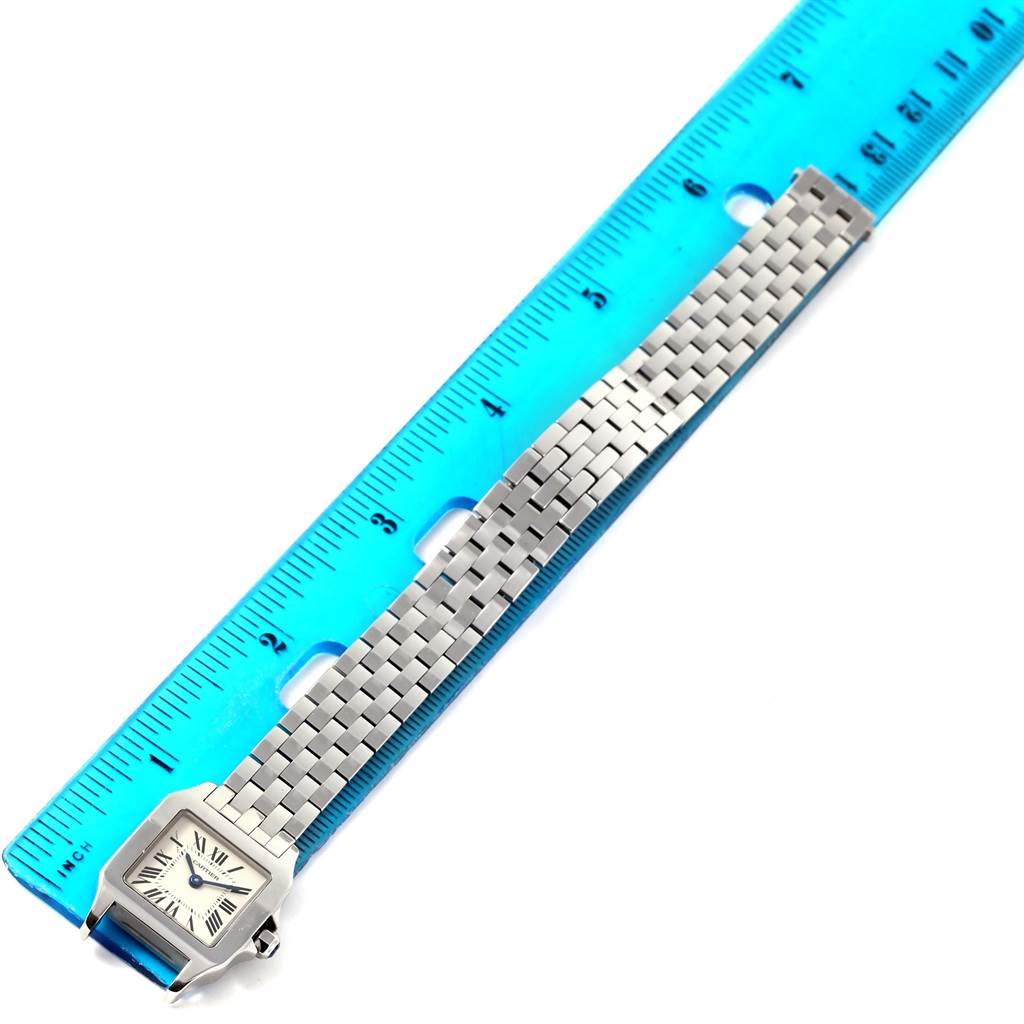 The image shows the Cartier Santos Demoiselle W25064Z5 Men's Stainless Steel Silver Dial W25064Z5 Men's Stainless Steel Silver Dial watch, displaying its face and entire metallic band alongside a ruler.