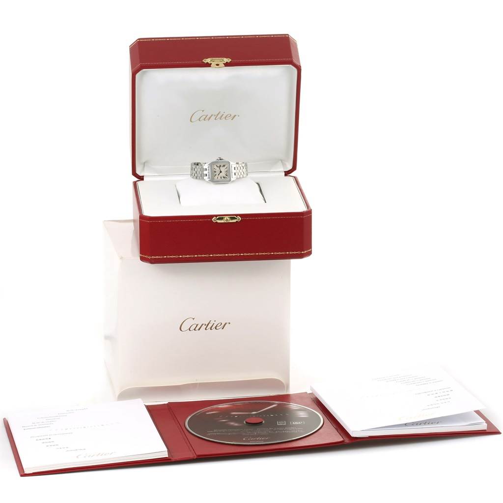 The image shows a Cartier Santos Demoiselle W25064Z5 Men's Stainless Steel Silver Dial W25064Z5 Men's Stainless Steel Silver Dial watch in its red box with additional booklets and a CD displayed in front.