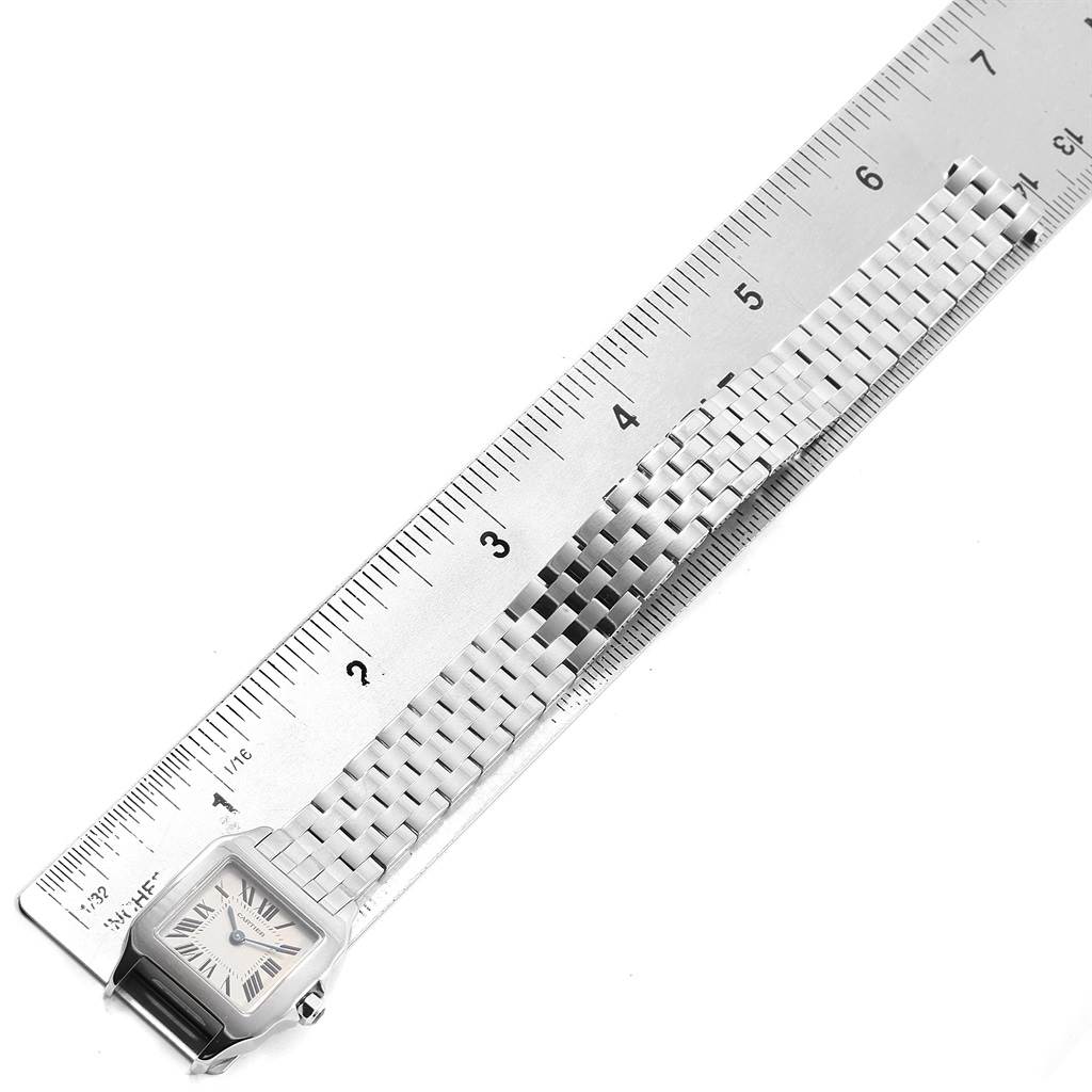 The Santos Demoiselle watch by Cartier is shown from a top-down angle, highlighting its face and bracelet against a ruler for scale.