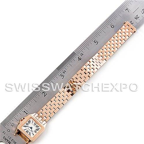 The image shows a Cartier Santos Demoiselle W25077X9 Women
s Rose Gold Silver Dial W25077X9 Women
s Rose Gold Silver Dial watch laid flat next to a ruler displaying its length, featuring its face and bracelet.