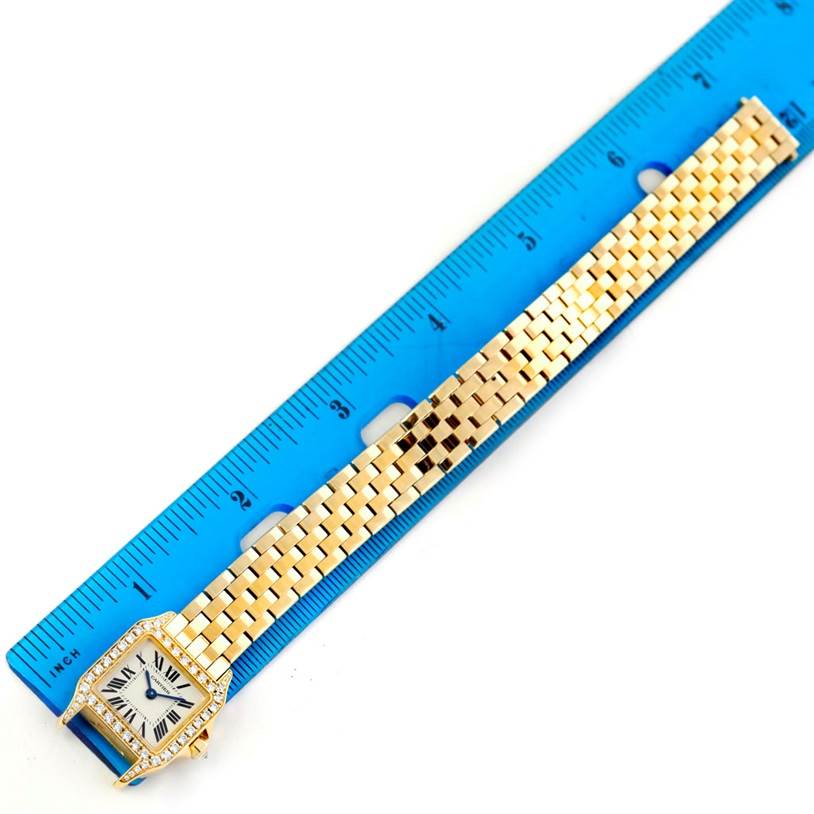 The Cartier Santos Demoiselle WF9001Y7 Women's Yellow Gold Silver Dial WF9001Y7 Women's Yellow Gold Silver Dial watch is shown from a top-down angle, next to a ruler for size reference.