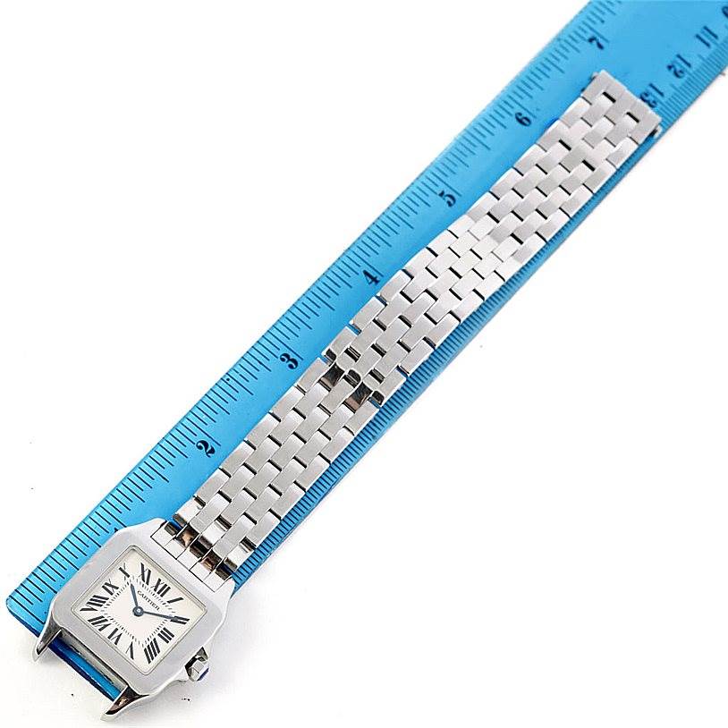The image shows the face and bracelet of a Cartier Santos Demoiselle W25065Z5 Women's Stainless Steel Silver Dial W25065Z5 Women's Stainless Steel Silver Dial watch at a top-down angle, placed beside a ruler.