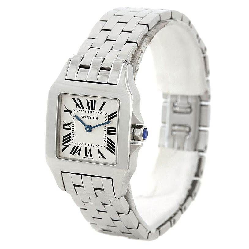 The image shows a Cartier Santos Demoiselle W25065Z5 Women
s Stainless Steel Silver Dial W25065Z5 Women
s Stainless Steel Silver Dial watch at an angle, highlighting the face, stainless steel bracelet, and crown with a blue stone.