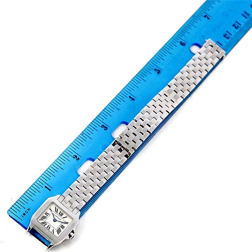 This image shows the face and bracelet of the Santos Demoiselle watch by Cartier, positioned next to a ruler for scale.