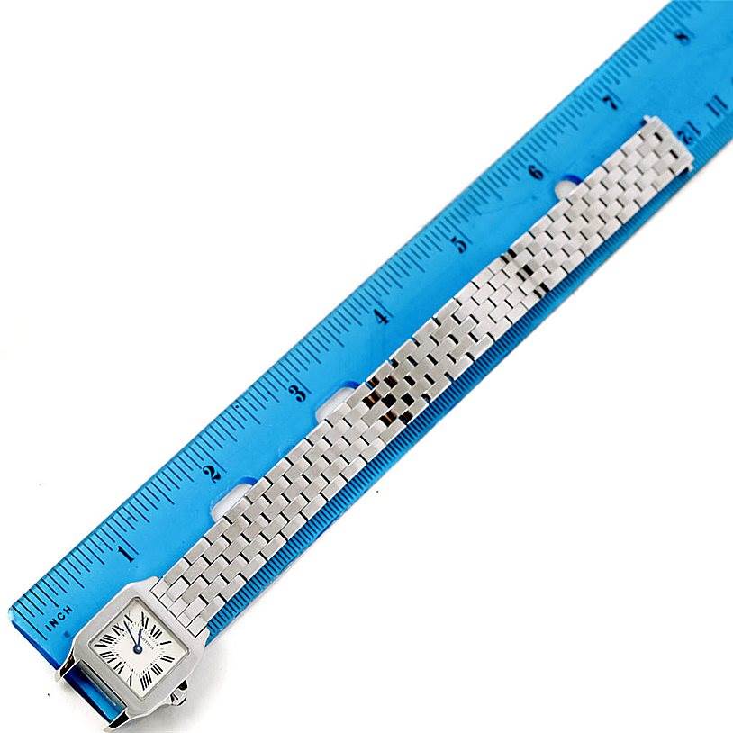 The image shows a Santos Demoiselle model by Cartier watch, laying flat alongside a ruler, displaying its full strap and face.