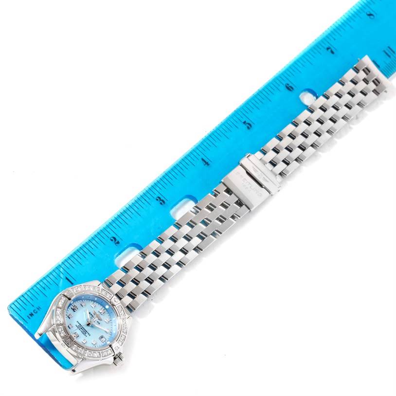 The image shows a Breitling A72345 Women
s Stainless Steel Mother of Pearl Dial A72345 Women
s Stainless Steel Mother of Pearl Dial Callisto Ladies Blue Mother of Pearl Diamond Watch A72345 laid next to a blue ruler for scale.