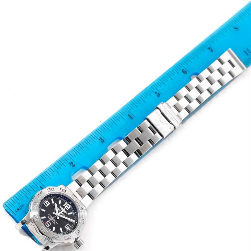 The Breitling A77380 Women's Stainless Steel Black Dial A77380 Women's Stainless Steel Black Dial Colt 33 Black Dial Stainless Steel Ladies Watch A77380 is shown flat with the dial, bracelet, and part of a blue ruler.