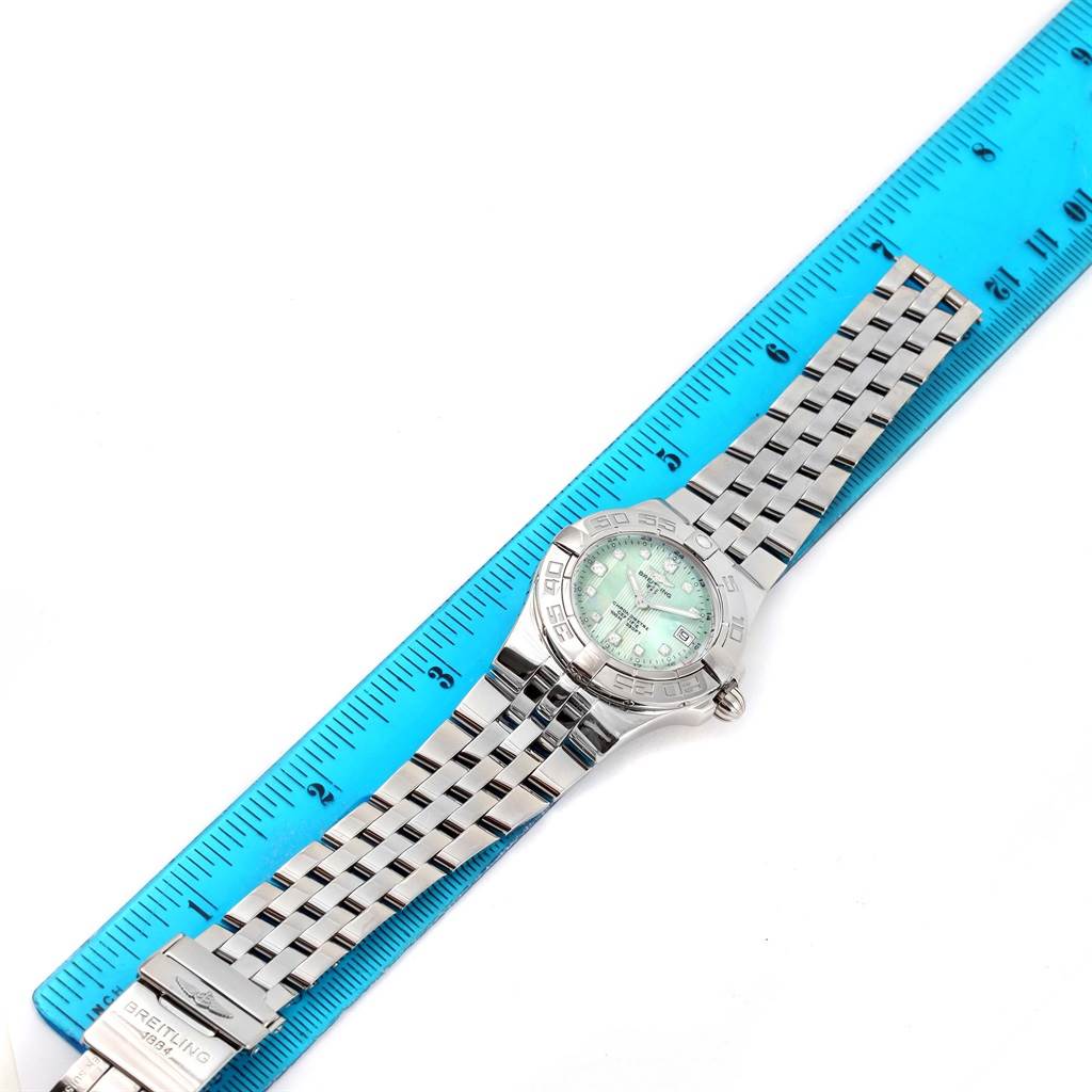 The Breitling A71340 Women's Stainless Steel Mother of Pearl Dial A71340 Women's Stainless Steel Mother of Pearl Dial Starliner Green Mother of Pearl Diamond Ladies Watch A71340 is displayed flat with its band extended next to a blue ruler.