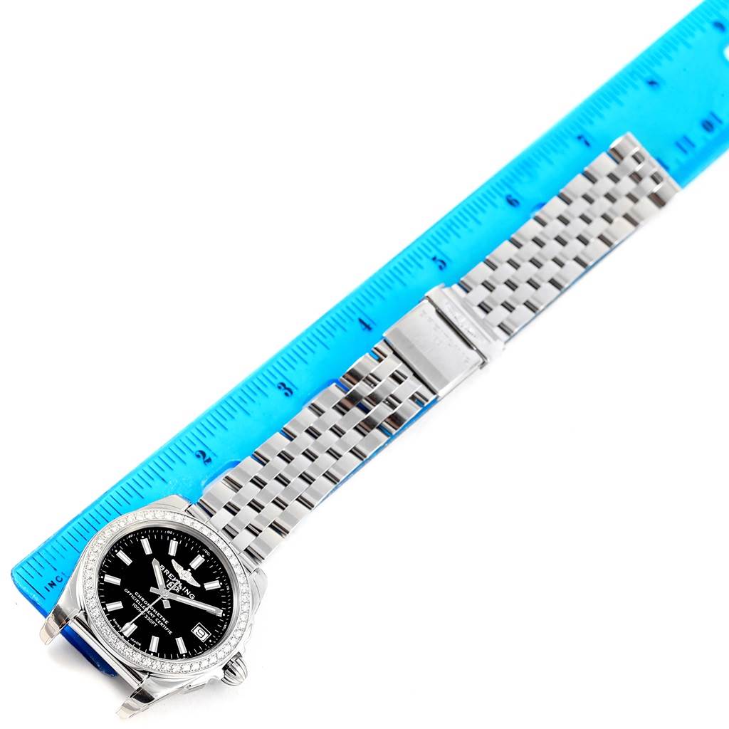 The Breitling W7433012-A780-376A Women
s Stainless Steel Black Dial W7433012-A780-376A Women
s Stainless Steel Black Dial Galactic 36 Black Dial Diamond Ladies Watch W74330 is shown from above, along with its metal bracelet and a blue ruler.