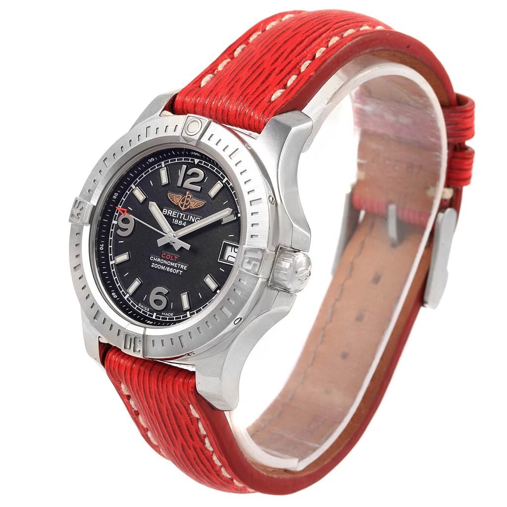 The Breitling A74389 Women's Stainless Steel Black Dial A74389 Women's Stainless Steel Black Dial Colt 36 Quartz Steel Men's Watch A74389 is shown at a tilted front angle, highlighting its black dial, bezel, and red strap.