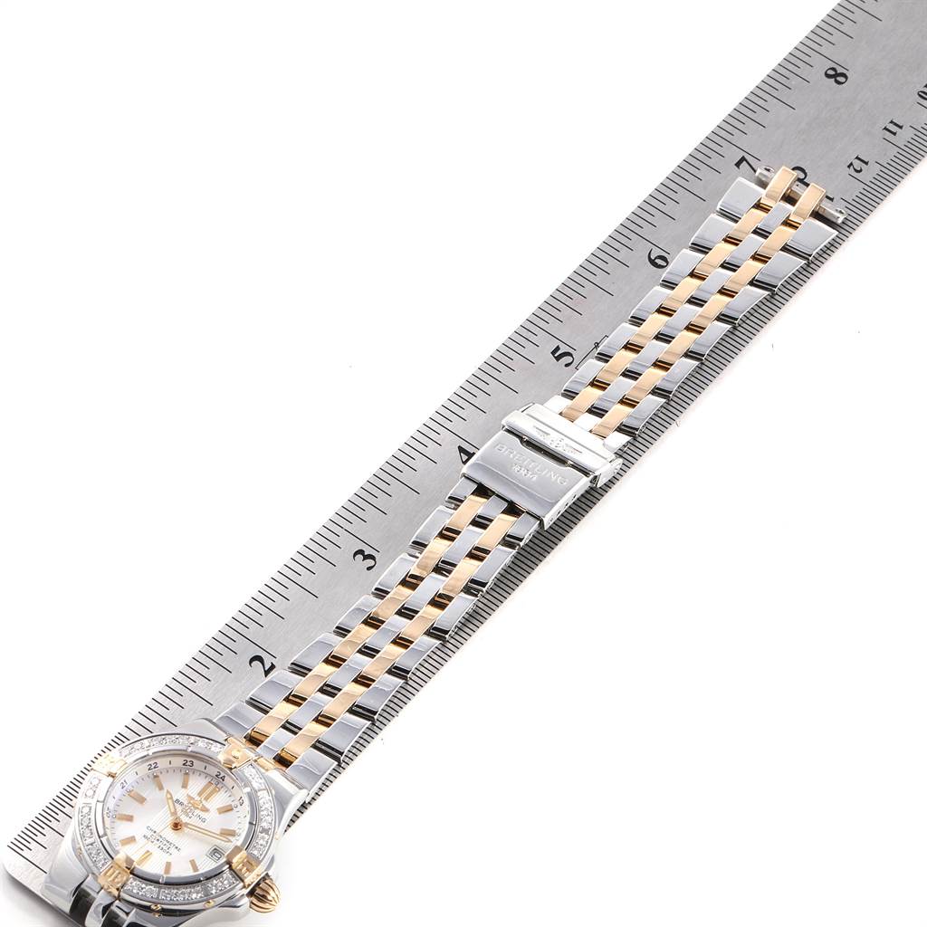 The Breitling B71340 Women's Steel and Gold (two tone) Mother of Pearl Dial B71340 Women's Steel and Gold (two tone) Mother of Pearl Dial Starliner Steel Yellow Gold MOP Diamond Ladies Watch B71340 is shown flat, highlighting the band along a ruler for measurement.