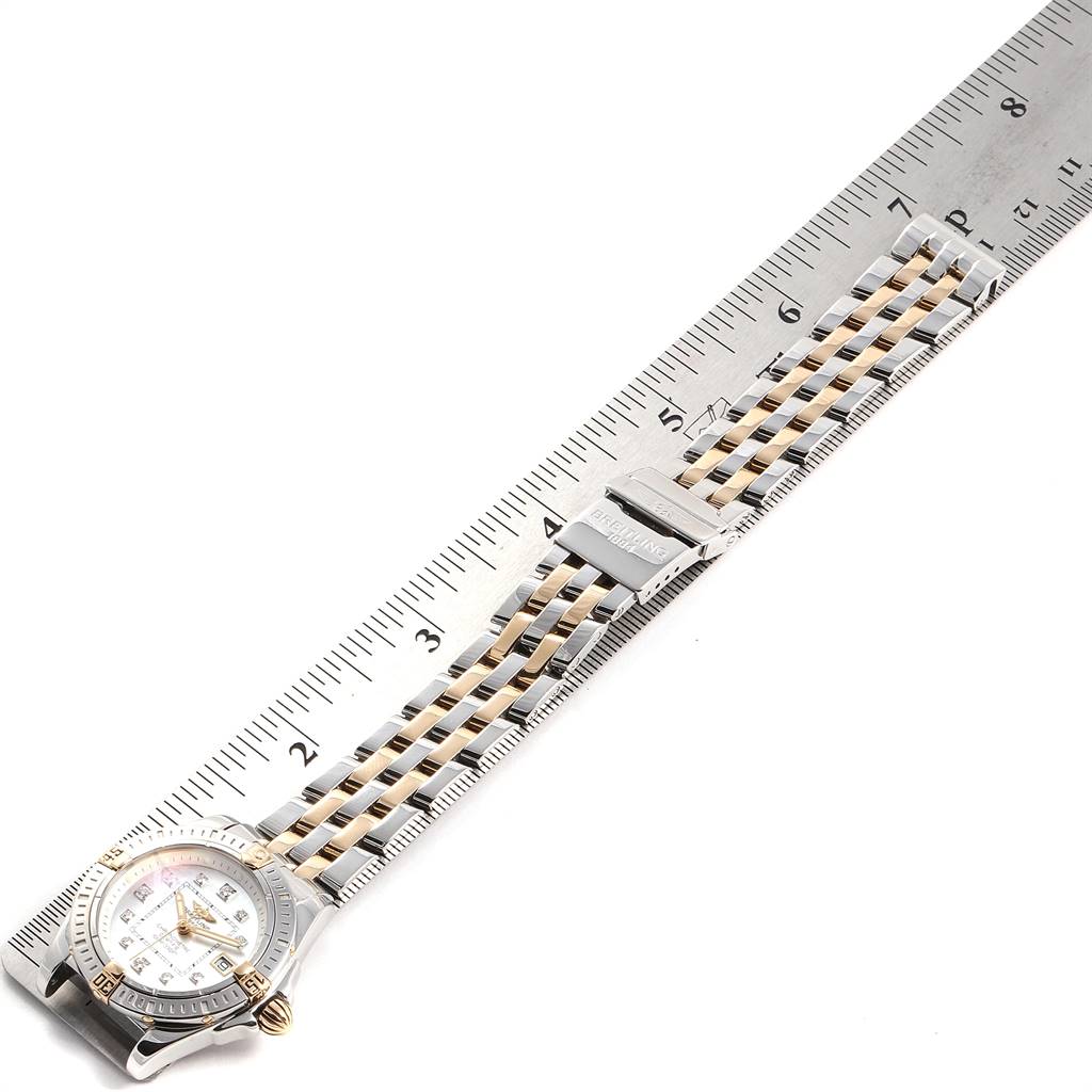 This image shows the Breitling B71356 Women's Steel and Gold (two tone) Mother of Pearl Dial B71356 Women's Steel and Gold (two tone) Mother of Pearl Dial Cockpit Steel Yellow Gold Diamond Ladies Watch B71356 laid flat next to a ruler, featuring the dial and bracelet.