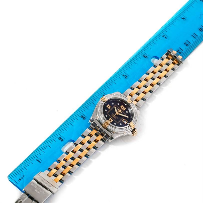 The image shows a top-down view of the Breitling B71356 Women
s Steel and Gold (two tone) Black Dial B71356 Women
s Steel and Gold (two tone) Black Dial Cockpit Ladies Steel 18K Yellow Gold Diamond Watch B71356, alongside a blue ruler for scale.