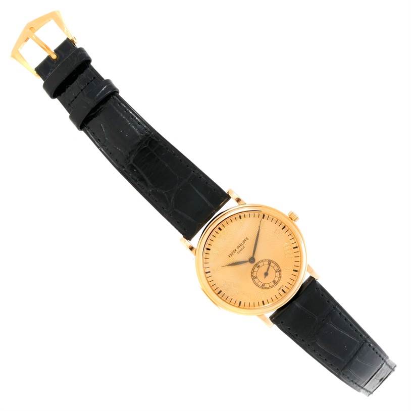 The image shows a Patek Philippe Calatrava 5022 Men's Yellow Gold Champagne Dial 5022 Men's Yellow Gold Champagne Dial watch from a top-down angle, displaying its face, dial, hands, and black leather strap.