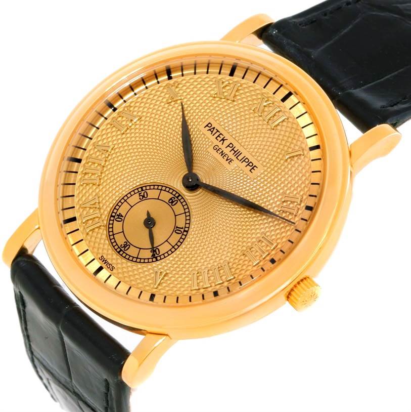 The image shows a Patek Philippe Calatrava 5022 Men's Yellow Gold Champagne Dial 5022 Men's Yellow Gold Champagne Dial watch from a slight top angle, highlighting the gold dial, black leather strap, and intricate detailing.