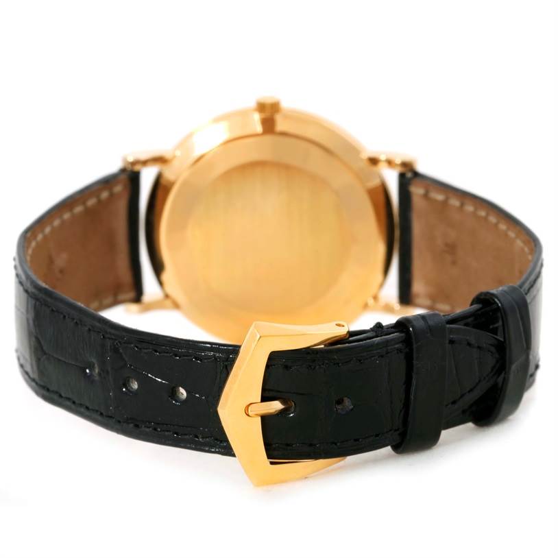 The image shows the back view of a Patek Philippe Calatrava 5022 Men's Yellow Gold Champagne Dial 5022 Men's Yellow Gold Champagne Dial watch, highlighting its gold case and black leather strap with a gold buckle.