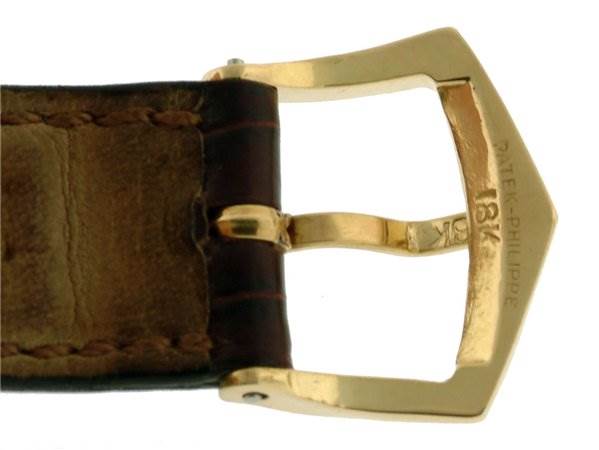 This image shows a close-up of the leather strap and gold buckle of a Vintage Patek Philippe watch.