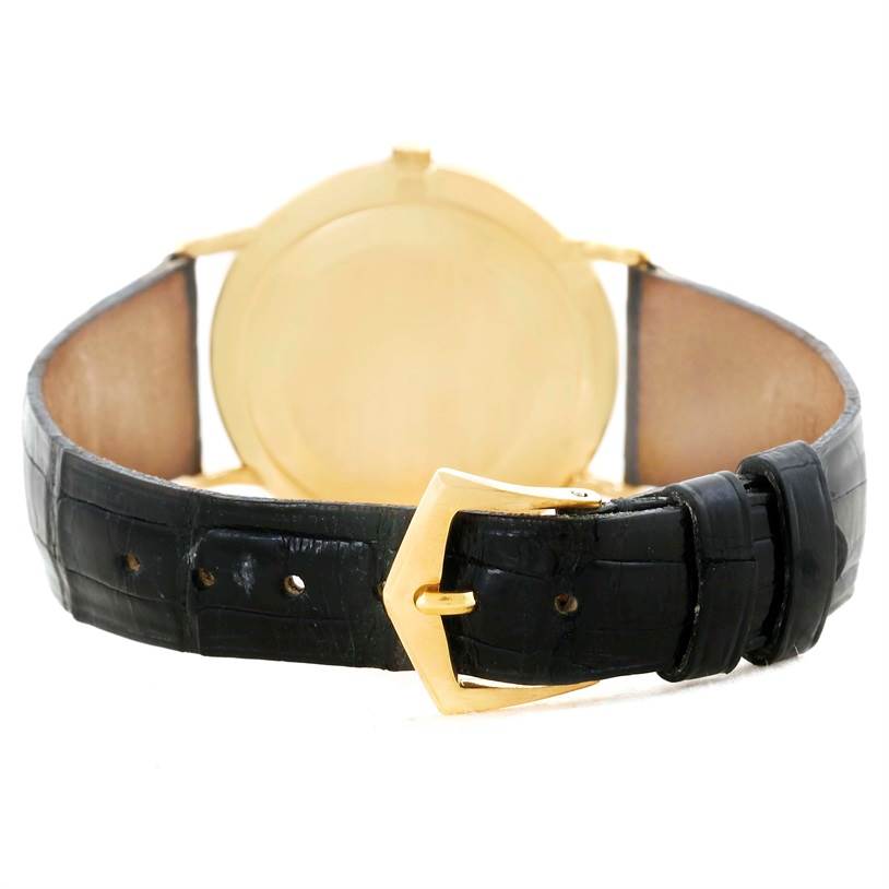The image shows the backside of a Calatrava model by Patek Philippe, highlighting the gold case back and black leather strap with a gold buckle.