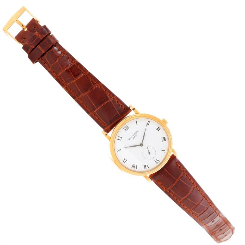 The image shows a Patek Philippe Calatrava 3919 Men's Yellow Gold White Dial 3919 Men's Yellow Gold White Dial watch from a top-down angle, featuring a gold case, white dial, and brown leather strap.