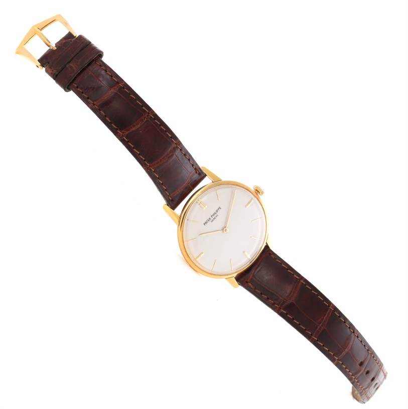 The image shows a Patek Philippe Vintage model watch, featuring a gold case, white dial, and a brown leather strap, viewed from above.