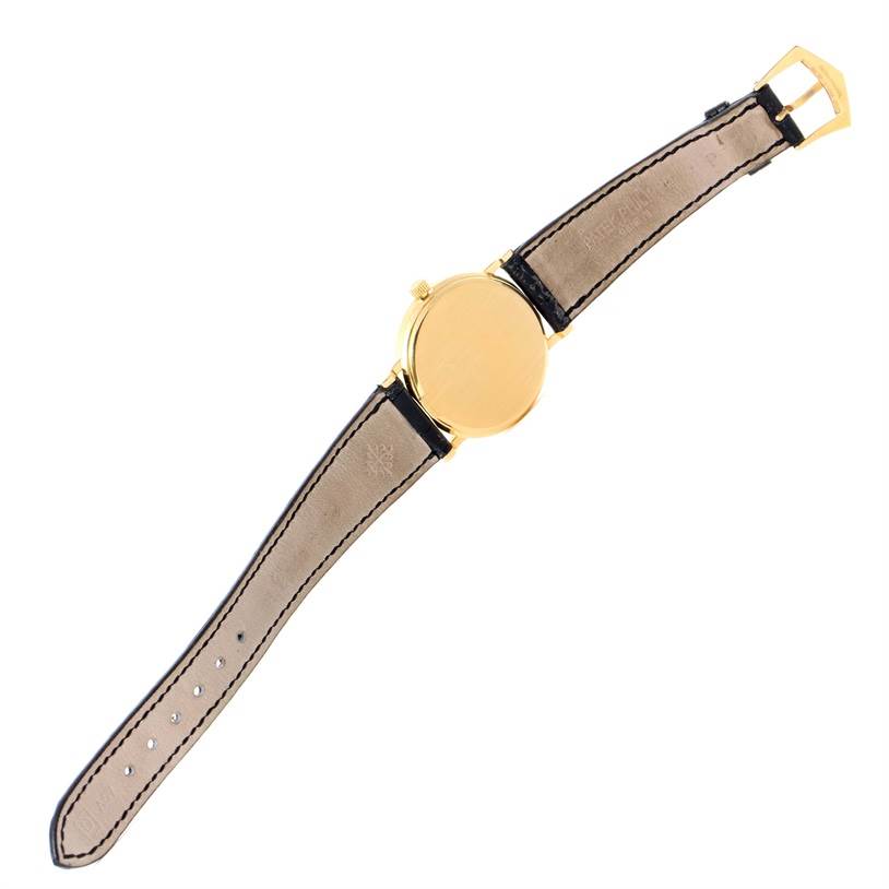 This image shows a Patek Philippe Calatrava 3802 Men's Yellow Gold White Dial 3802 Men's Yellow Gold White Dial watch from the back, highlighting the leather strap and the gold case.