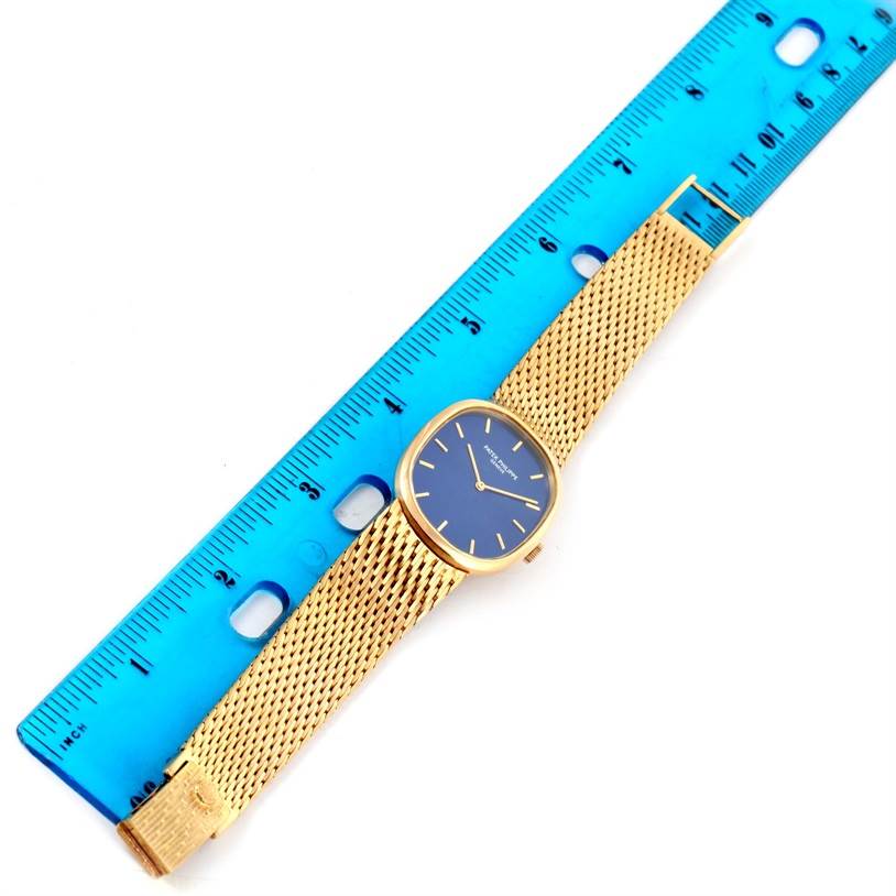 The image displays the Patek Philippe Golden Ellipse 3748 Men's Yellow Gold Blue Dial 3748 Men's Yellow Gold Blue Dial watch from a top-down angle, with its strap and face next to a ruler.