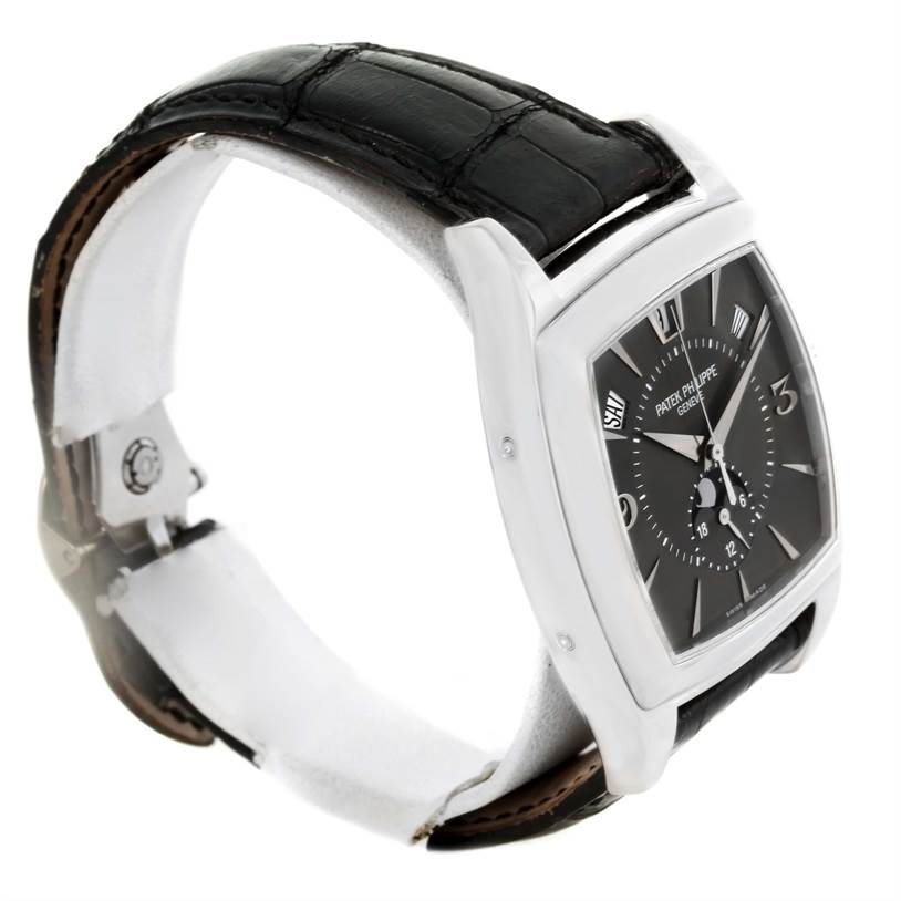 The image shows a side-angle view of the Patek Philippe Gondolo 5135G Men's White Gold Black Dial 5135G Men's White Gold Black Dial watch, highlighting its black leather strap and rectangular face.