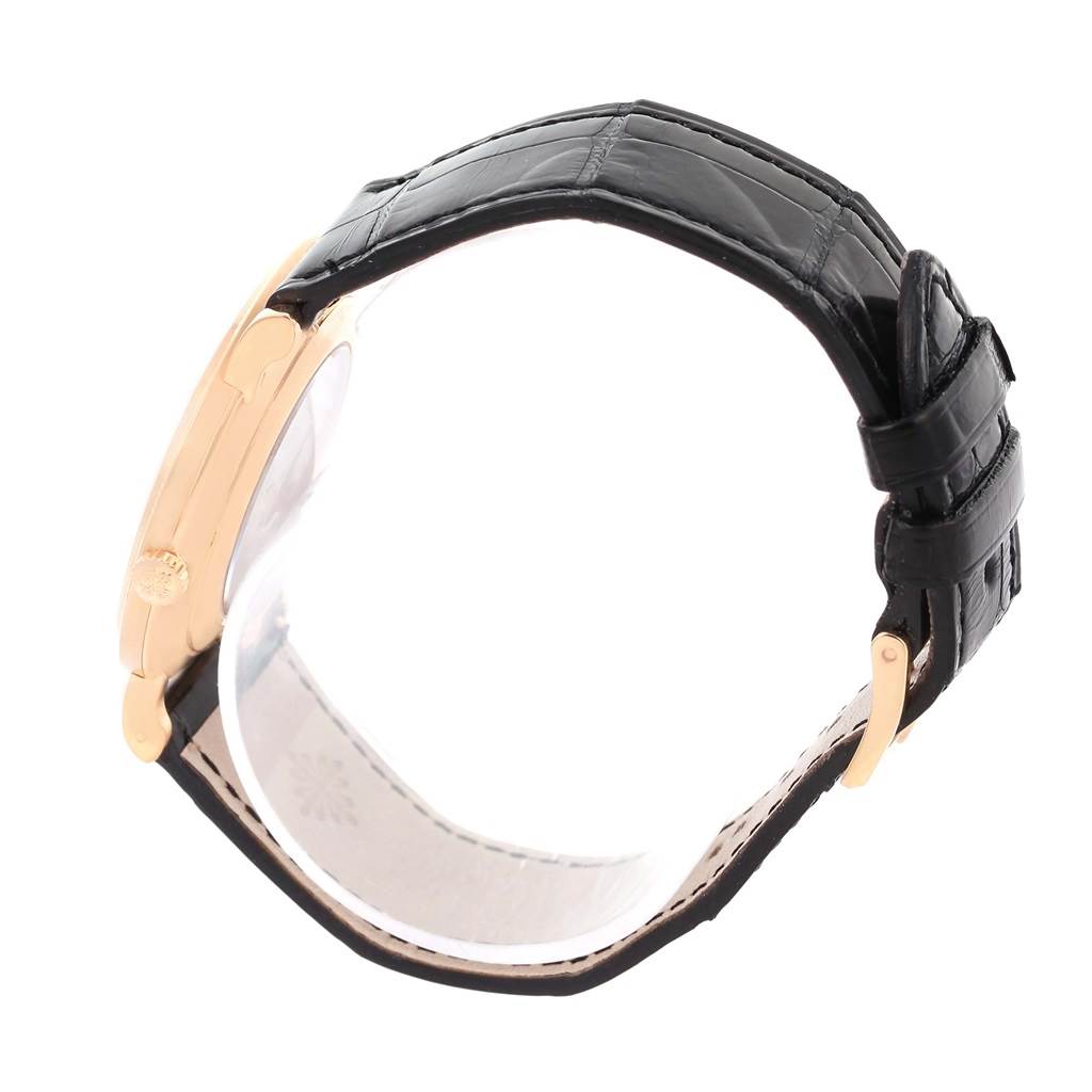 The image shows a side view of a Patek Philippe Calatrava 5119 Men
s Rose Gold White Dial 5119 Men
s Rose Gold White Dial watch, featuring its black leather strap and gold case.