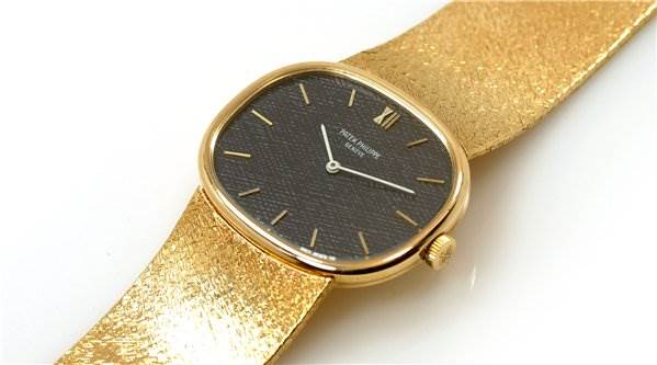 The image shows a top-down view of a Patek Philippe 3845/2 YEAR 1978 Yellow Gold Black Dial 3845/2 YEAR 1978 Yellow Gold Black Dial Vintage Men 18k Gold Ellipse 3845/2 watch, highlighting its black dial and textured gold band.