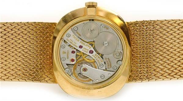 The image shows the back view of a Patek Philippe 3845/2 YEAR 1978 Yellow Gold Black Dial 3845/2 YEAR 1978 Yellow Gold Black Dial Vintage Men 18k Gold Ellipse 3845/2 Year 1978 watch, exposing its internal mechanism and gears.