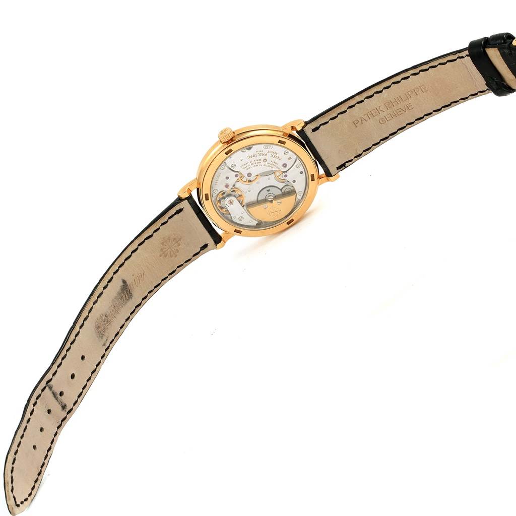 The image shows the back view of a Patek Philippe Calatrava 5120J Men's Yellow Gold White Dial 5120J Men's Yellow Gold White Dial watch, highlighting its mechanical movement and leather strap.