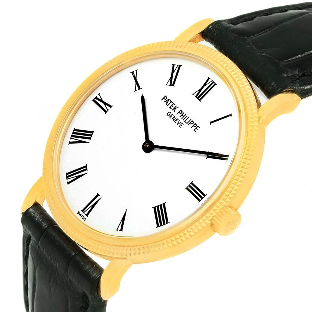 This image shows a Patek Philippe Calatrava 5120J Men's Yellow Gold White Dial 5120J Men's Yellow Gold White Dial watch at an angled view, highlighting its dial, hands, crown, and part of the leather strap.