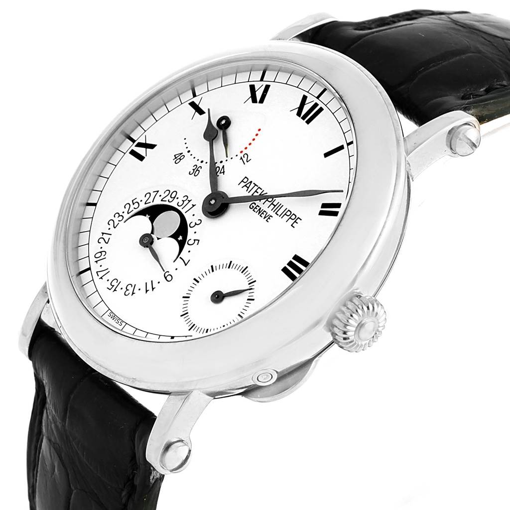 The Patek Philippe Complications 5054 Men's White Gold White Dial 5054 Men's White Gold White Dial watch is shown at a tilted angle featuring its face, crown, and part of the leather strap.