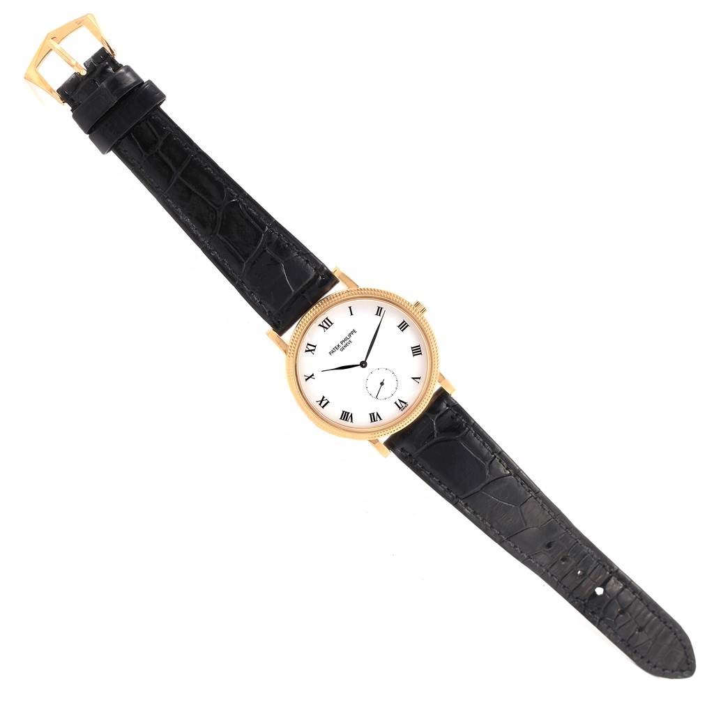 The Patek Philippe Calatrava 3919 Men's Rose Gold White Dial 3919 Men's Rose Gold White Dial watch is shown from a top-down angle, displaying its black leather strap and white dial with Roman numerals.