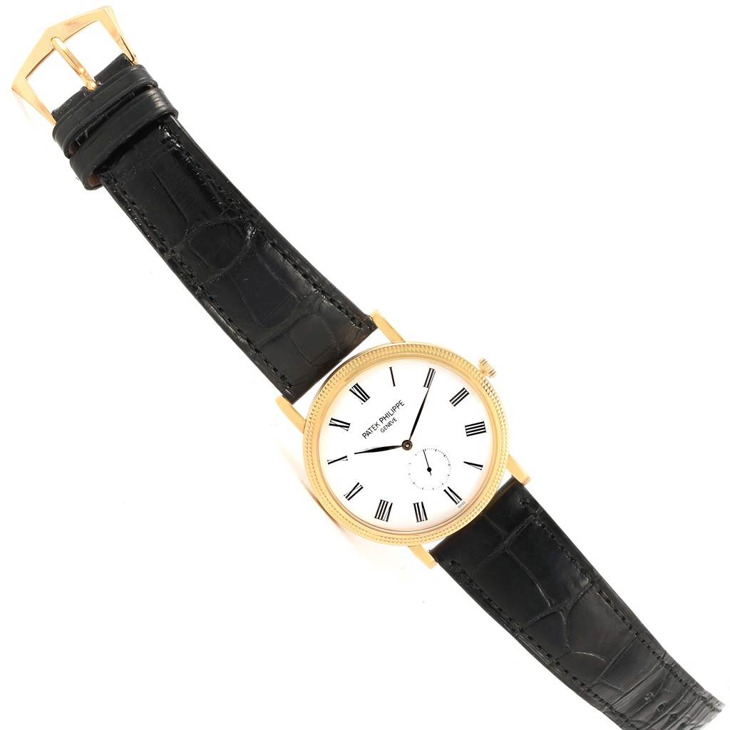 The image shows a Patek Philippe Calatrava 5119J Men's Yellow Gold White Dial 5119J Men's Yellow Gold White Dial watch viewed from a slightly tilted top angle, featuring the black leather strap and round dial.