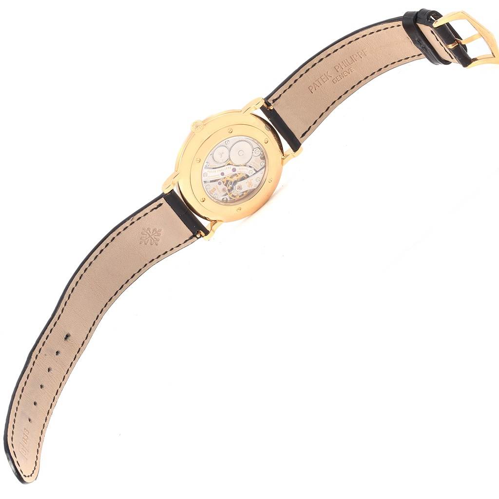 The image shows the back of a Patek Philippe Calatrava 5119J Men's Yellow Gold White Dial 5119J Men's Yellow Gold White Dial watch, revealing its inner mechanism and leather strap.