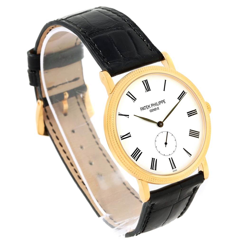The image shows a Patek Philippe Calatrava 5119J Men's Yellow Gold White Dial 5119J Men's Yellow Gold White Dial watch from a three-quarter angle, highlighting its face, gold case, and black leather strap.