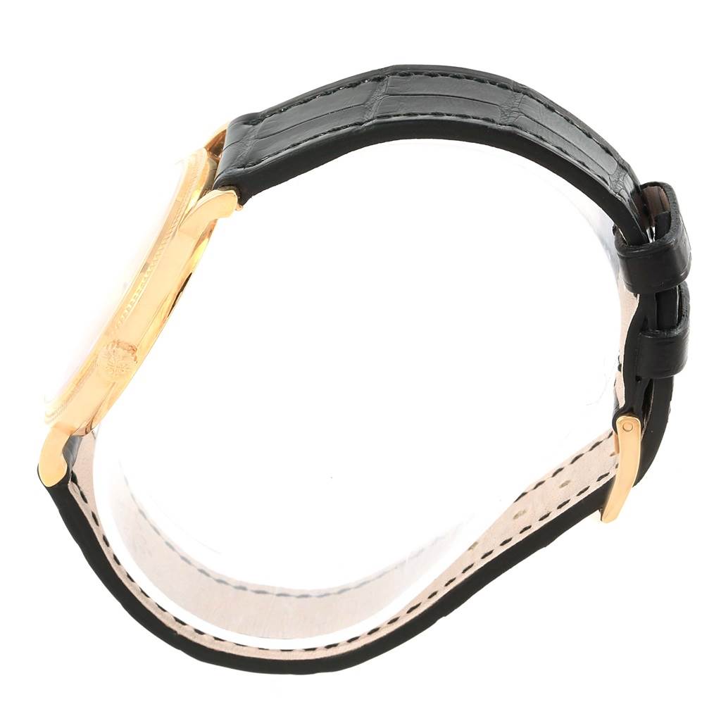 The image shows a side view of the Patek Philippe Calatrava 5120J Men's Yellow Gold White Dial 5120J Men's Yellow Gold White Dial watch, highlighting the gold case and black leather strap.