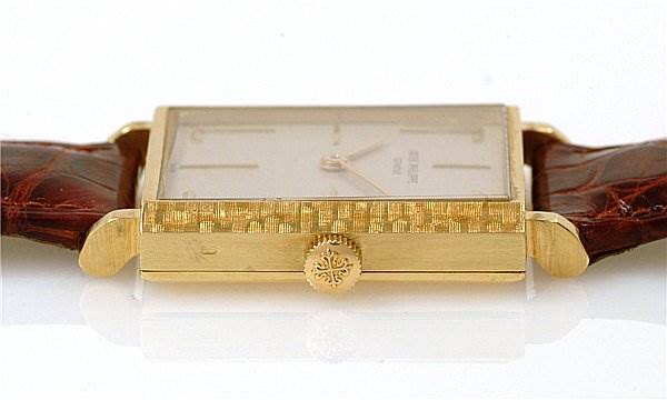 The image shows a side view of a Vintage Patek Philippe watch displaying its gold case, crown, and brown leather strap.