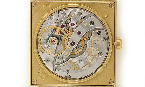 This image shows the intricate inner mechanism of a Vintage Patek Philippe watch, viewed from the back, highlighting gears and components.