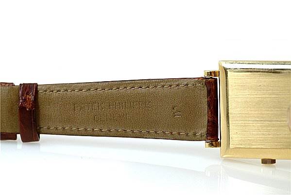 The image shows a close-up side view of a Vintage Patek Philippe watch, focusing on the beige leather strap and gold watch case.