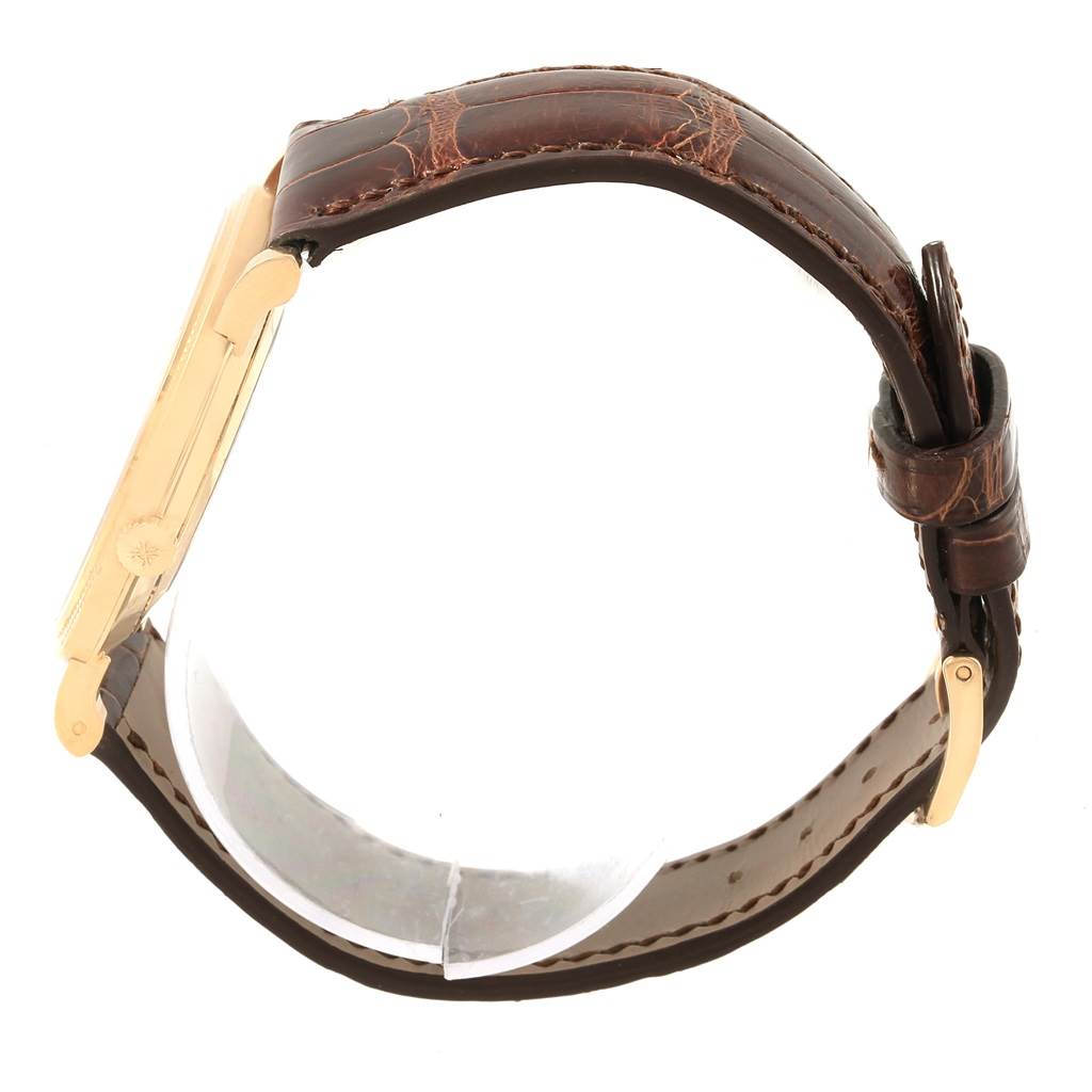 The image shows a side view of a Patek Philippe Calatrava 5119J Men's Yellow Gold White Dial 5119J Men's Yellow Gold White Dial wristwatch, highlighting its brown leather strap and gold case.