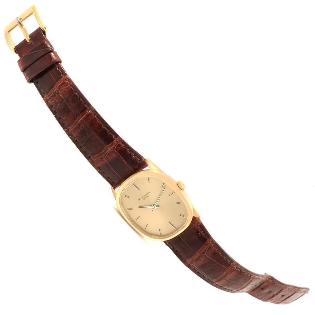 This image shows a Golden Ellipse model by Patek Philippe, displaying the watch face, crown, brown leather strap, and buckle in a tilted position.