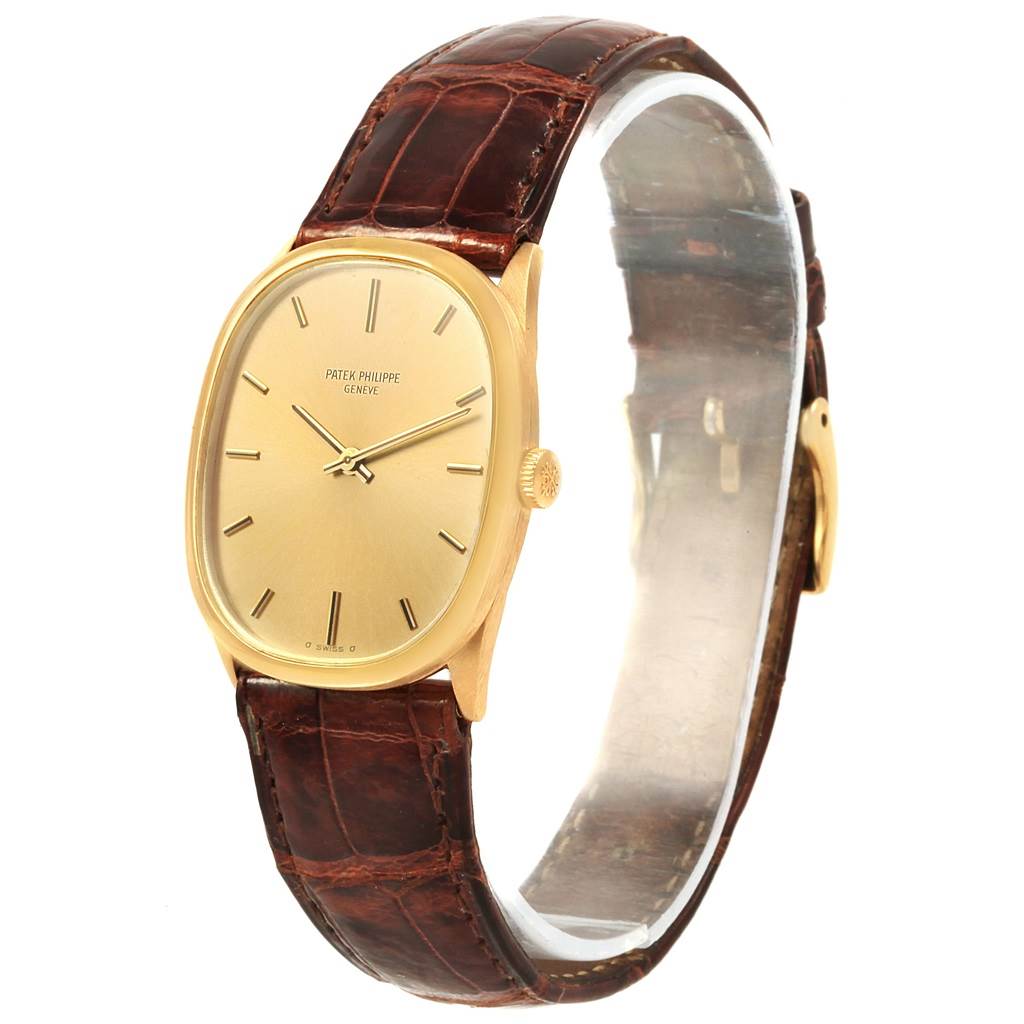 The Patek Philippe Golden Ellipse 3546 Men's Yellow Gold Champagne Dial 3546 Men's Yellow Gold Champagne Dial watch is shown at an angle displaying its face, gold case, brown leather strap, and side crown.