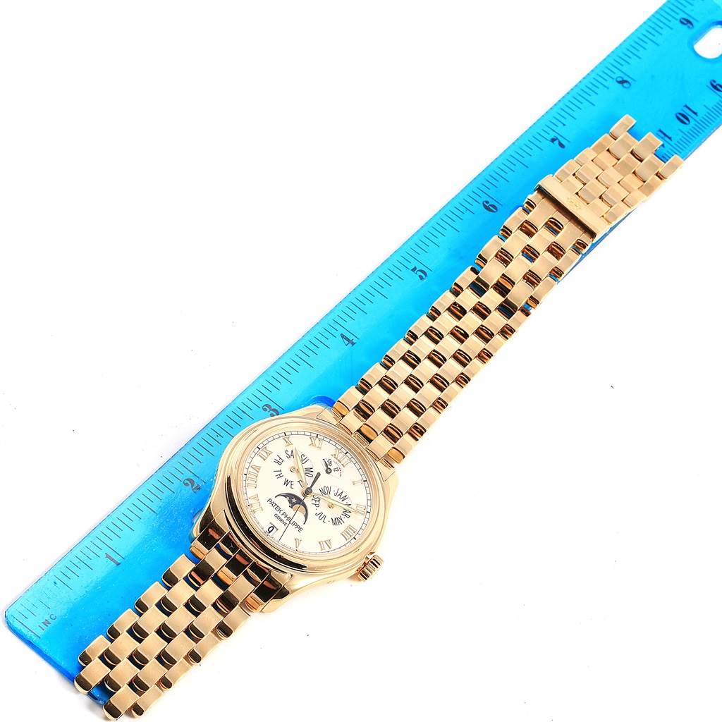 The image shows a top-down view of the Patek Philippe 5036 Men's Yellow Gold White Dial 5036 Men's Yellow Gold White Dial Annual Calendar Moonphase Yellow Gold Watch 5036 placed beside a blue ruler.