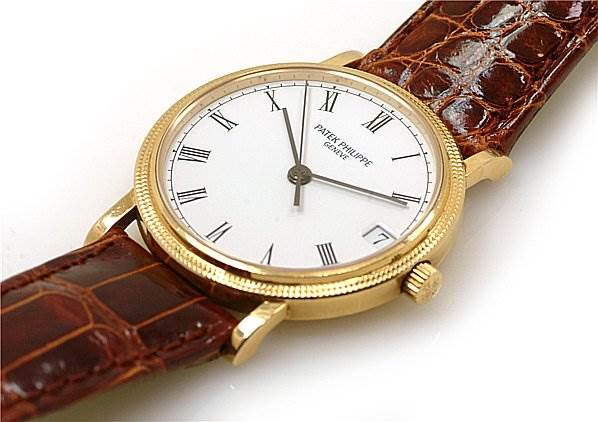 This image shows a Patek Philippe Calatrava 3802/200 Men's Yellow Gold White Dial 3802/200 Men's Yellow Gold White Dial watch from an angled top view, highlighting its white dial, gold case, and brown leather strap.