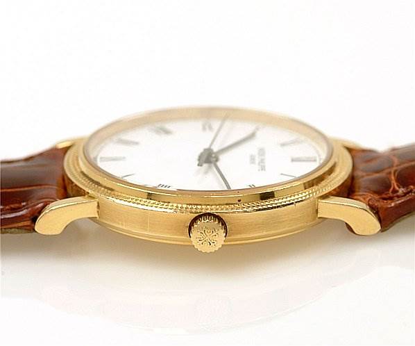 The image shows a side view of a Patek Philippe Calatrava 3802/200 Men's Yellow Gold White Dial 3802/200 Men's Yellow Gold White Dial watch, highlighting the crown, case, and part of the leather strap.